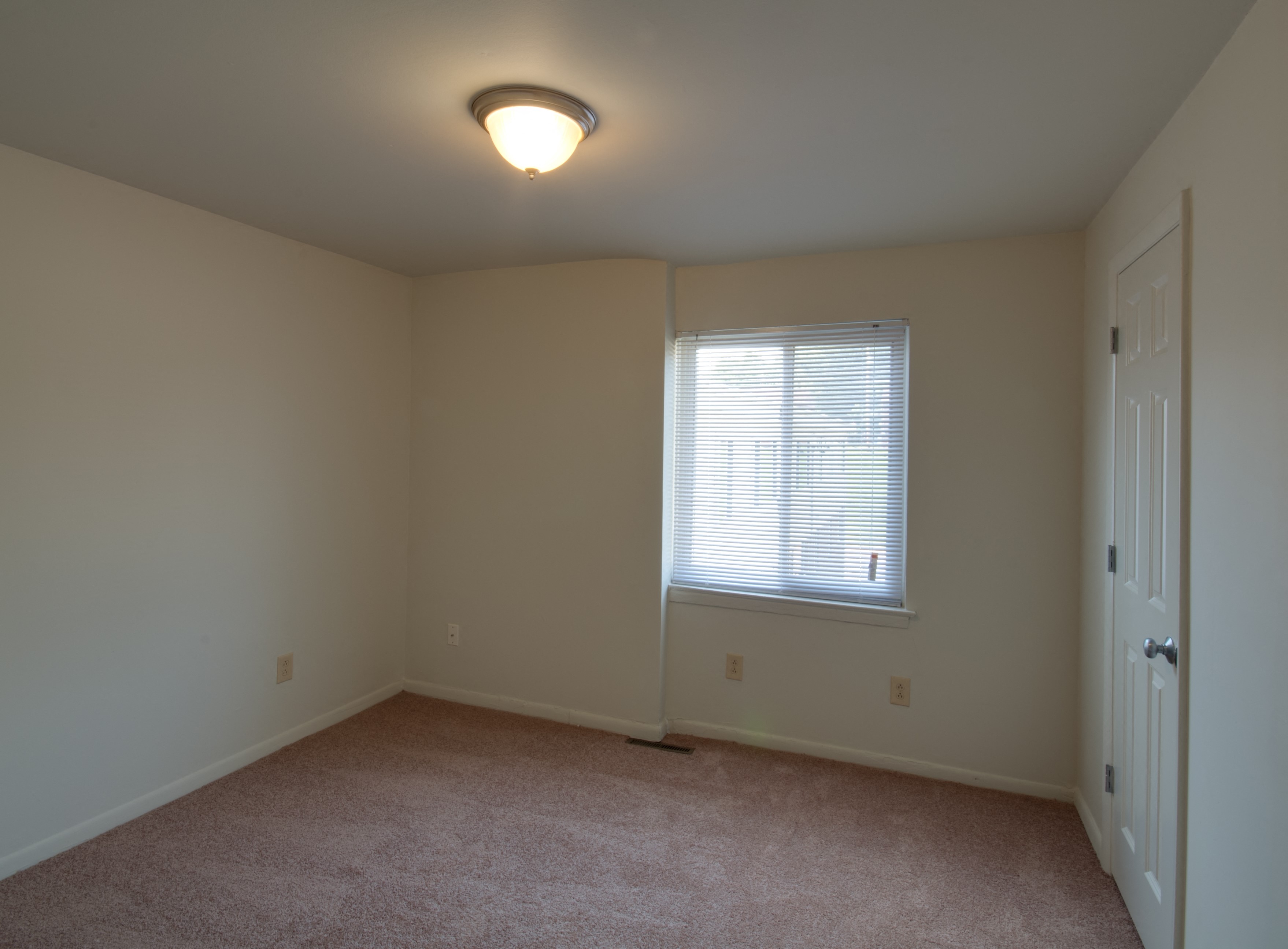 an empty living room with a window and a door