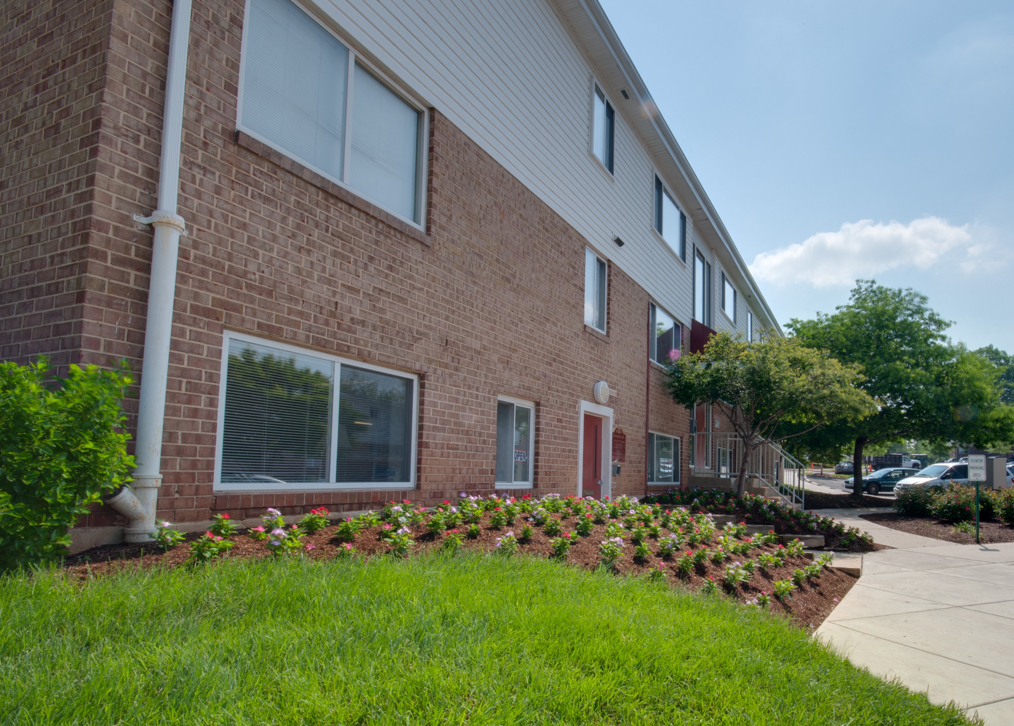 a brick apartment building with a flower garden in front of it
