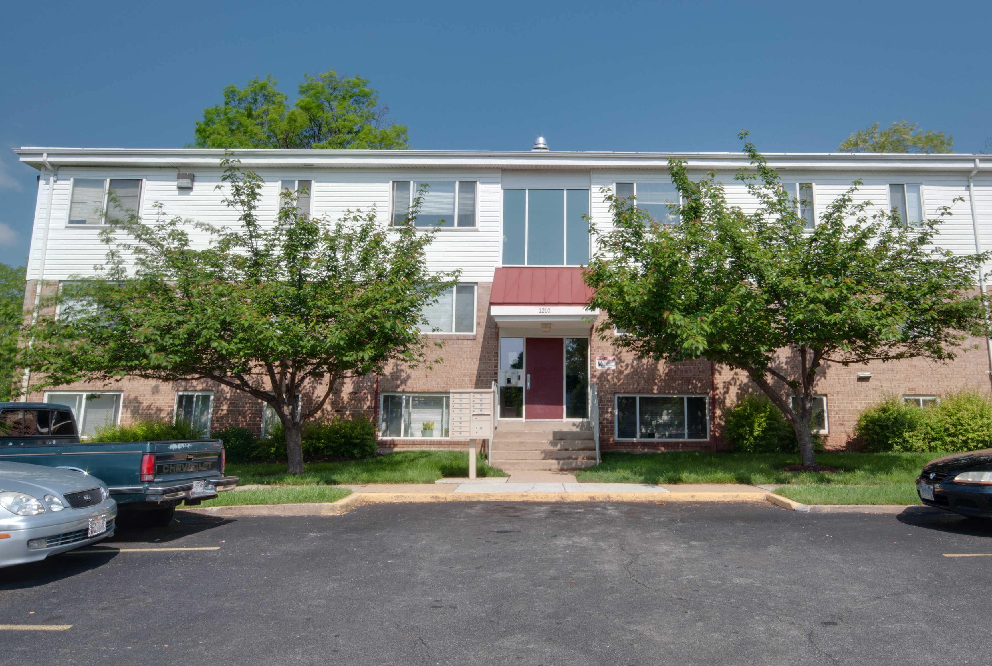 the front of a brick building with trees and a parking lot