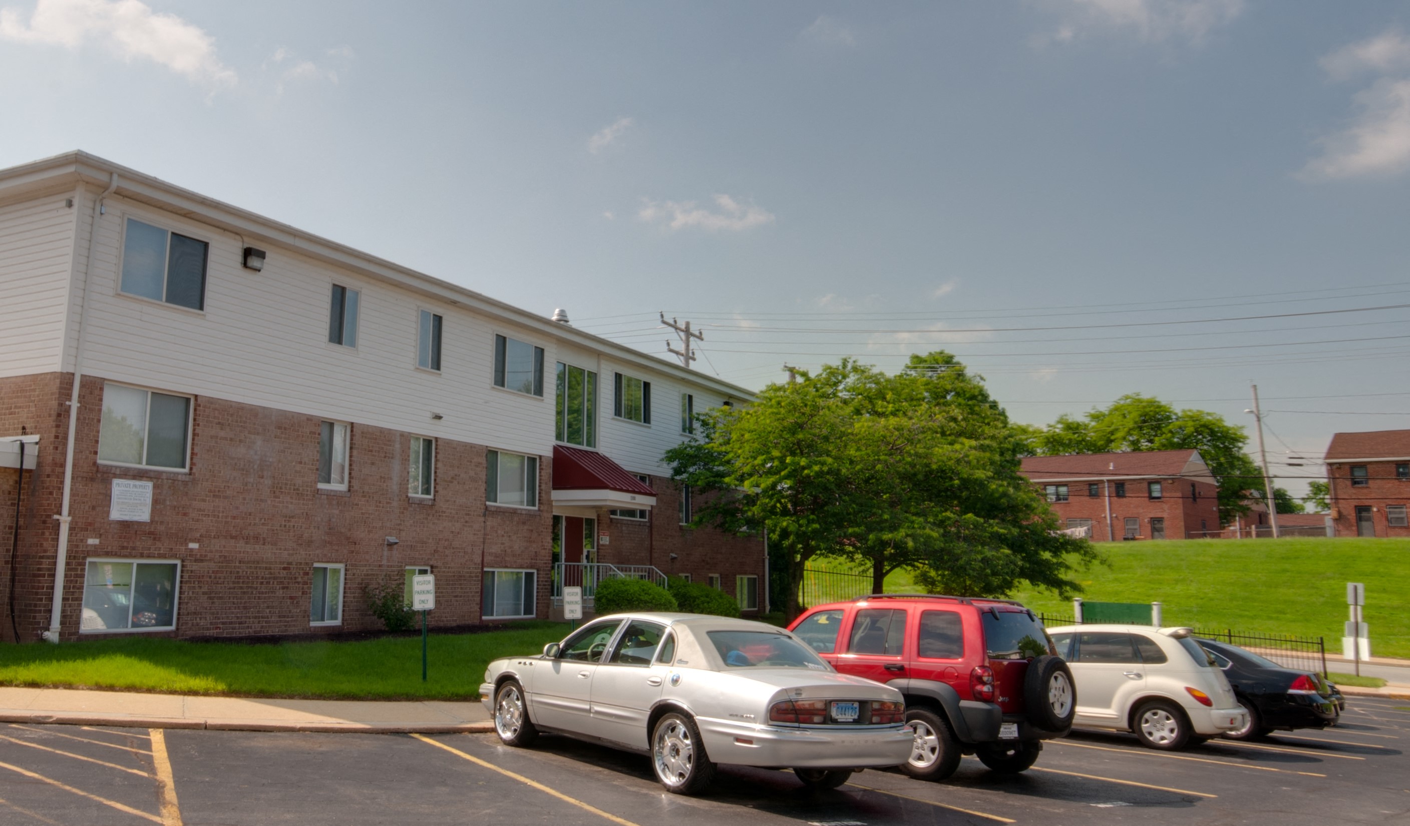 a parking lot filled with cars in front of an apartment building