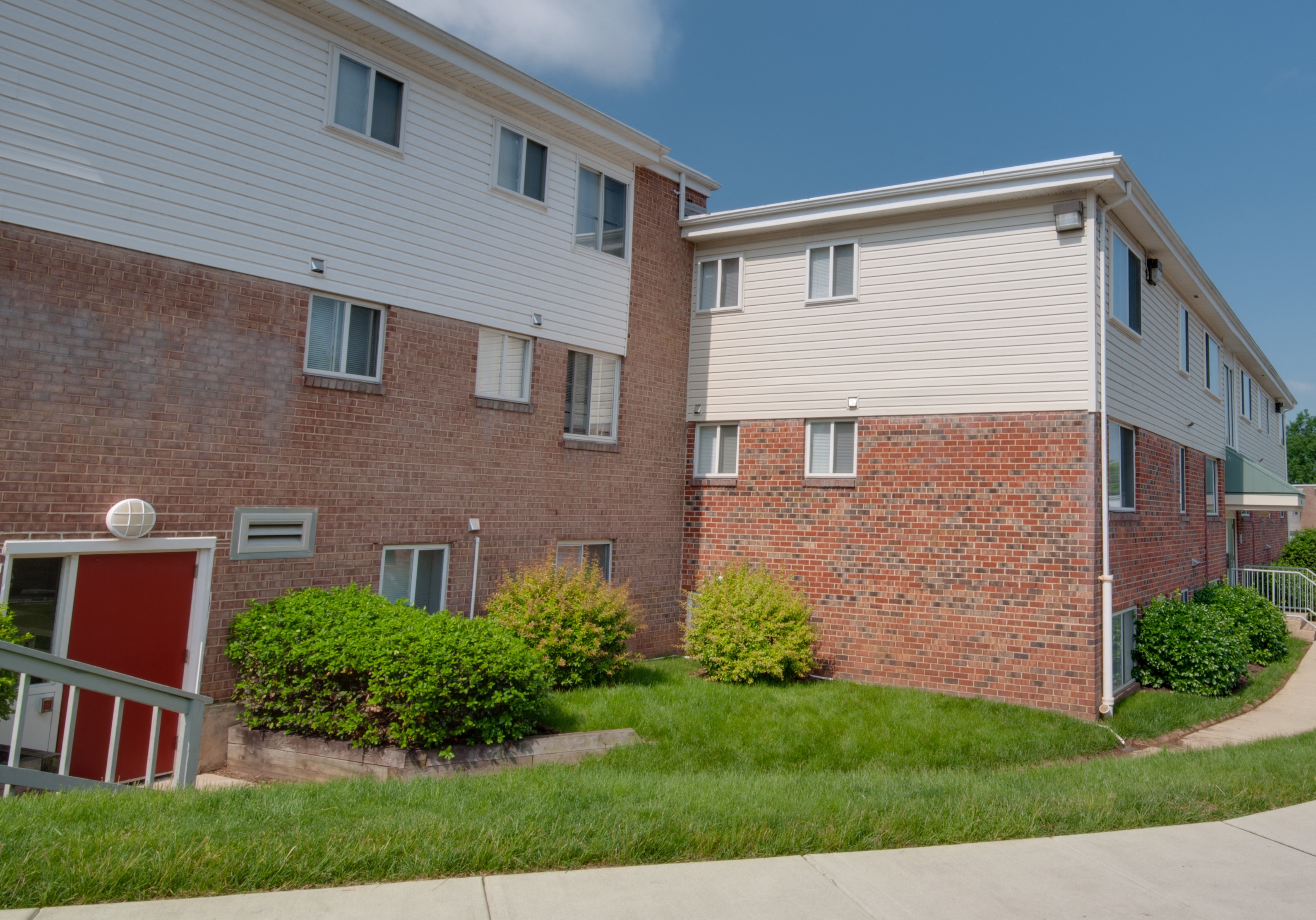 an apartment building with a red door and a sidewalk