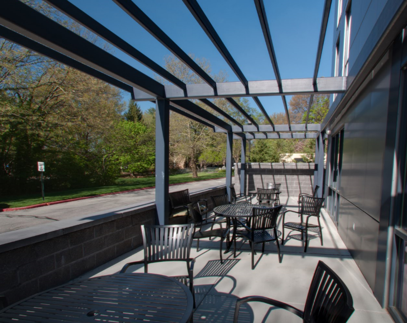 a patio with tables and chairs under a glass roof