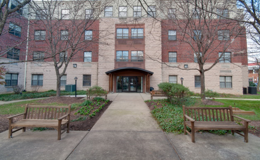 the front of a brick building with benches and a sidewalk