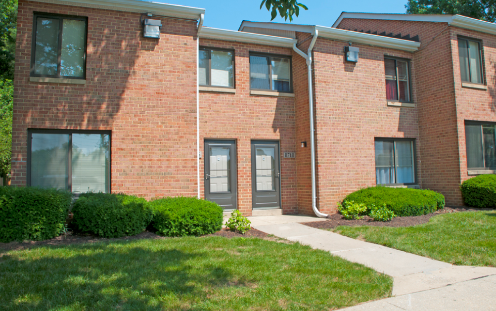 the front of a brick building with a sidewalk and grass