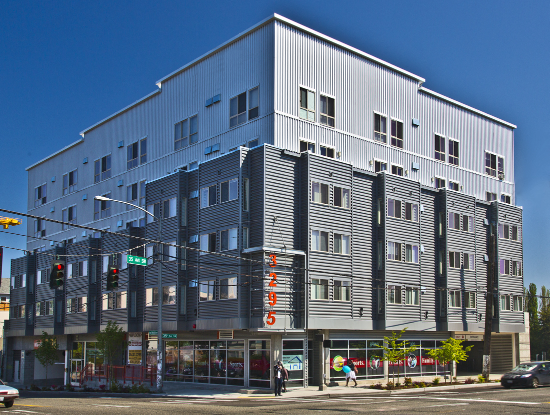 A large grey building with a flat roof and a balcony on the second floor.