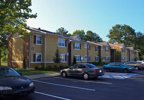 A black car is parked in a parking lot in front of a building.