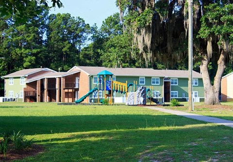 A playground is in front of a green building.