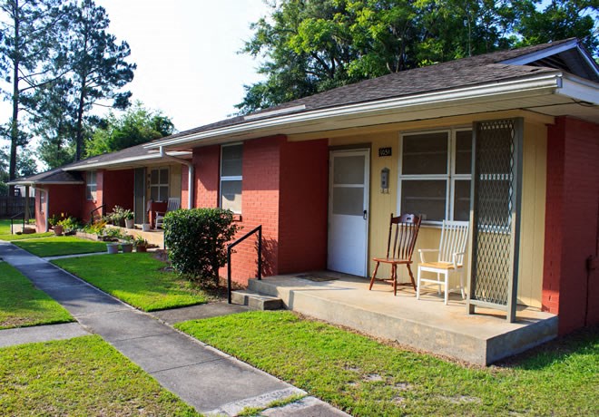 a porch with a rocking chair in front of a brick house
