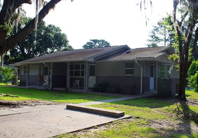 a house with a yard and trees in front of it