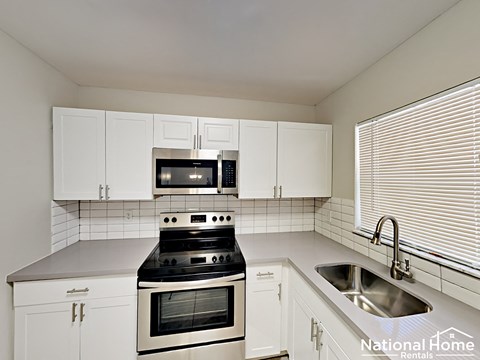A kitchen with white cabinets and a black stove top oven.