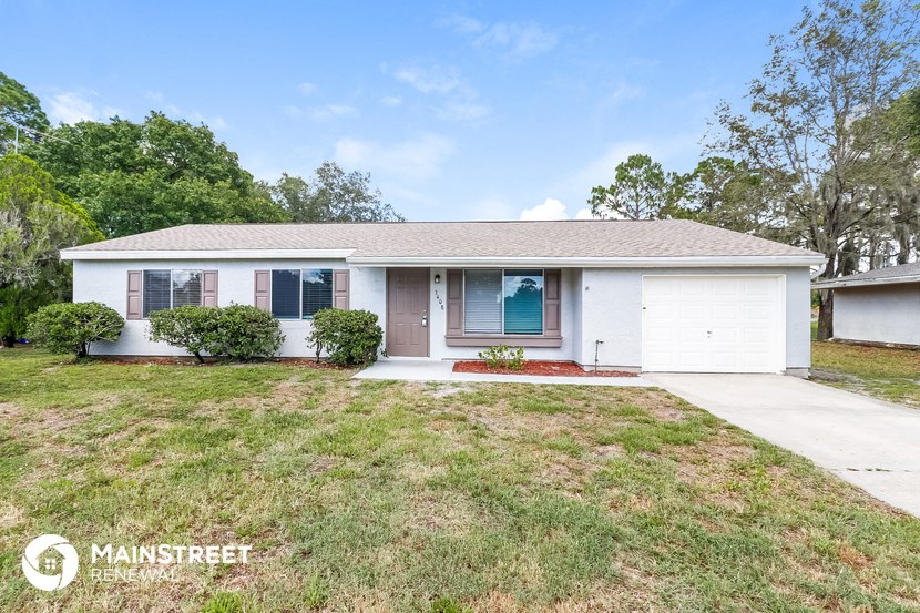 a small white house with a lawn and a driveway