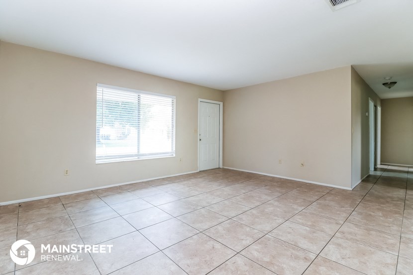 an empty living room with tiled floors and a window