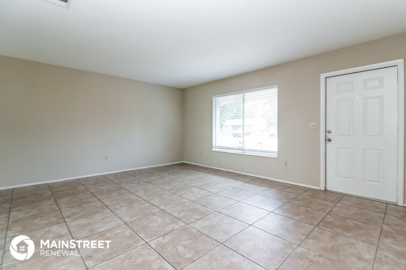 the living room of a home with a large tile floor and a white door