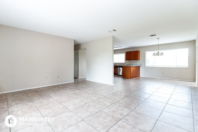 a large living room with tile flooring and a kitchen