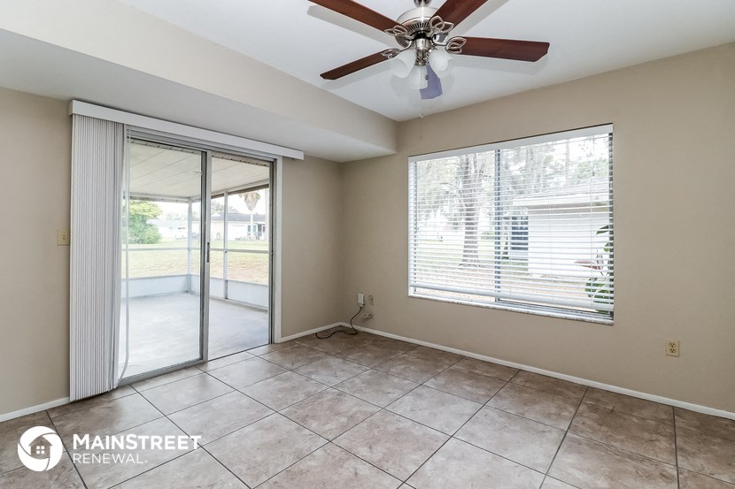 an empty living room with a ceiling fan and a sliding glass door