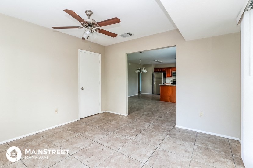 an empty living room with a ceiling fan and a tile floor