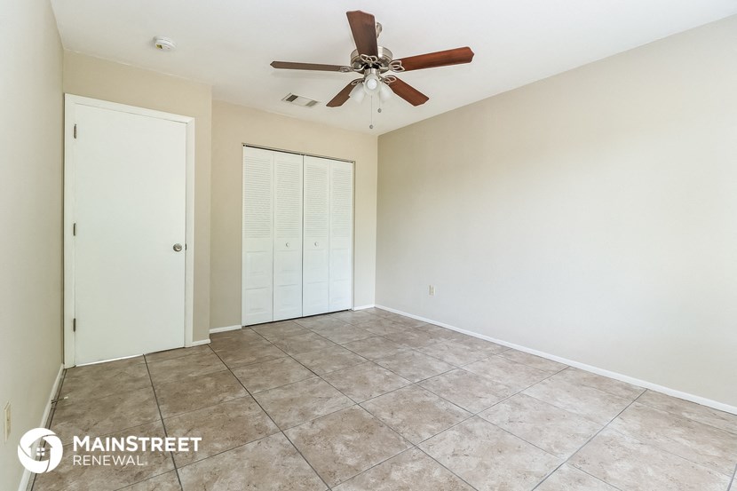 a empty living room with a ceiling fan and a tiled floor