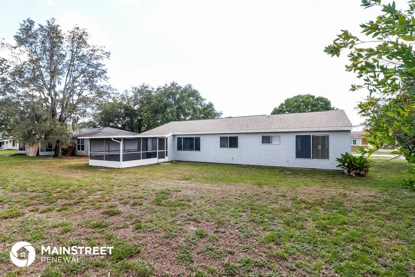 the back of a white house with a yard and trees