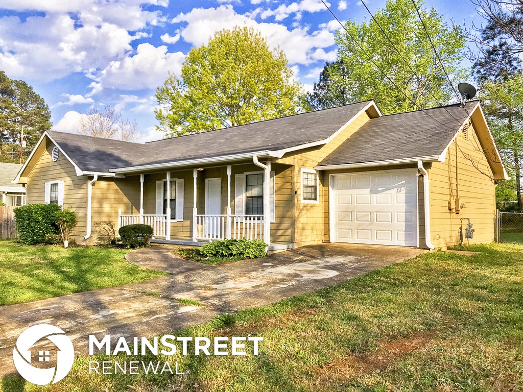 a small yellow house with a driveway and a white garage door