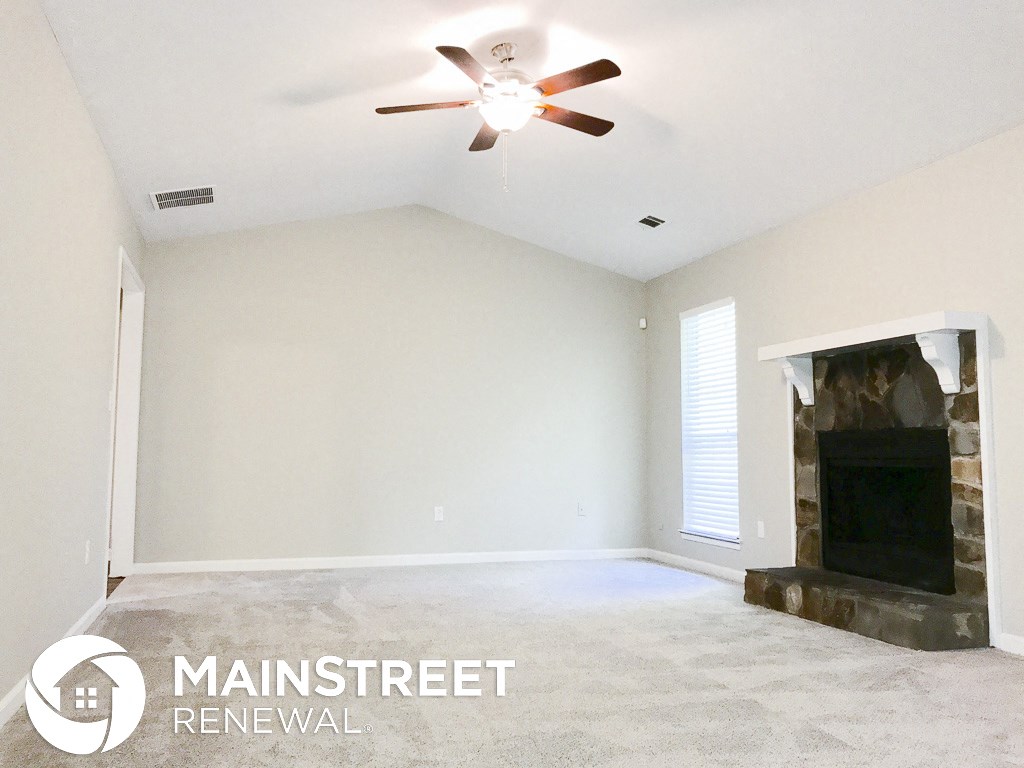 an empty living room with a fireplace and a ceiling fan