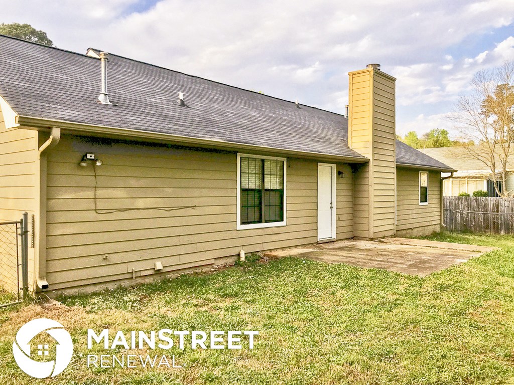 front view of a small yellow house with a yard and grass