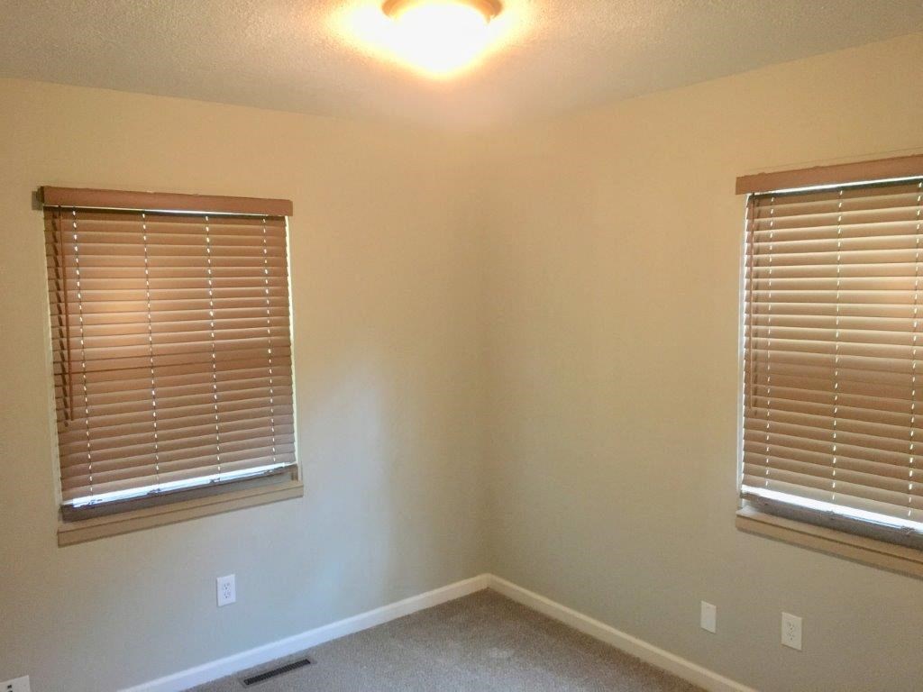 an empty room with two windows and a light