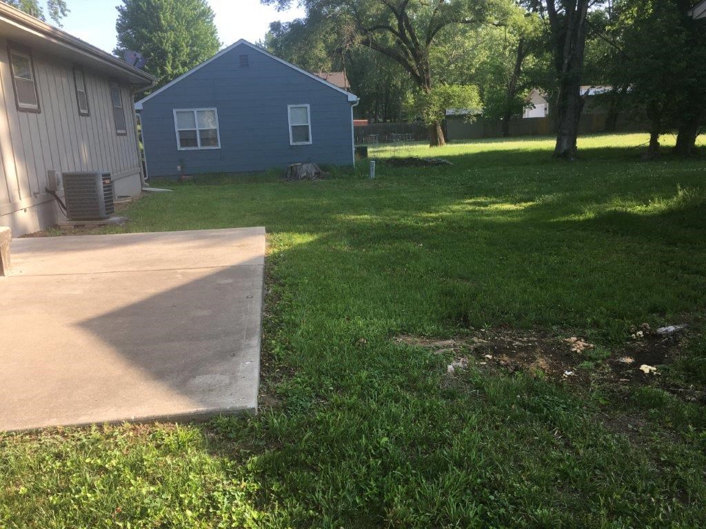 a backyard with a concrete driveway and a blue house