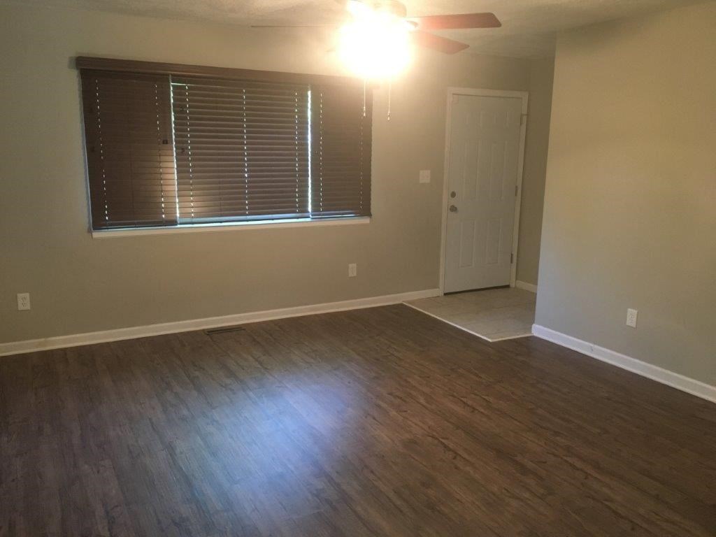 an empty living room with wood floors and a ceiling fan