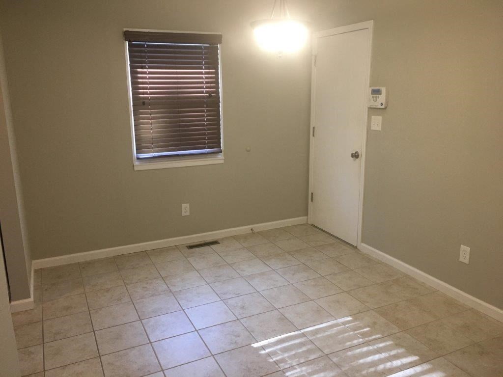 an empty room with a window and a tiled floor