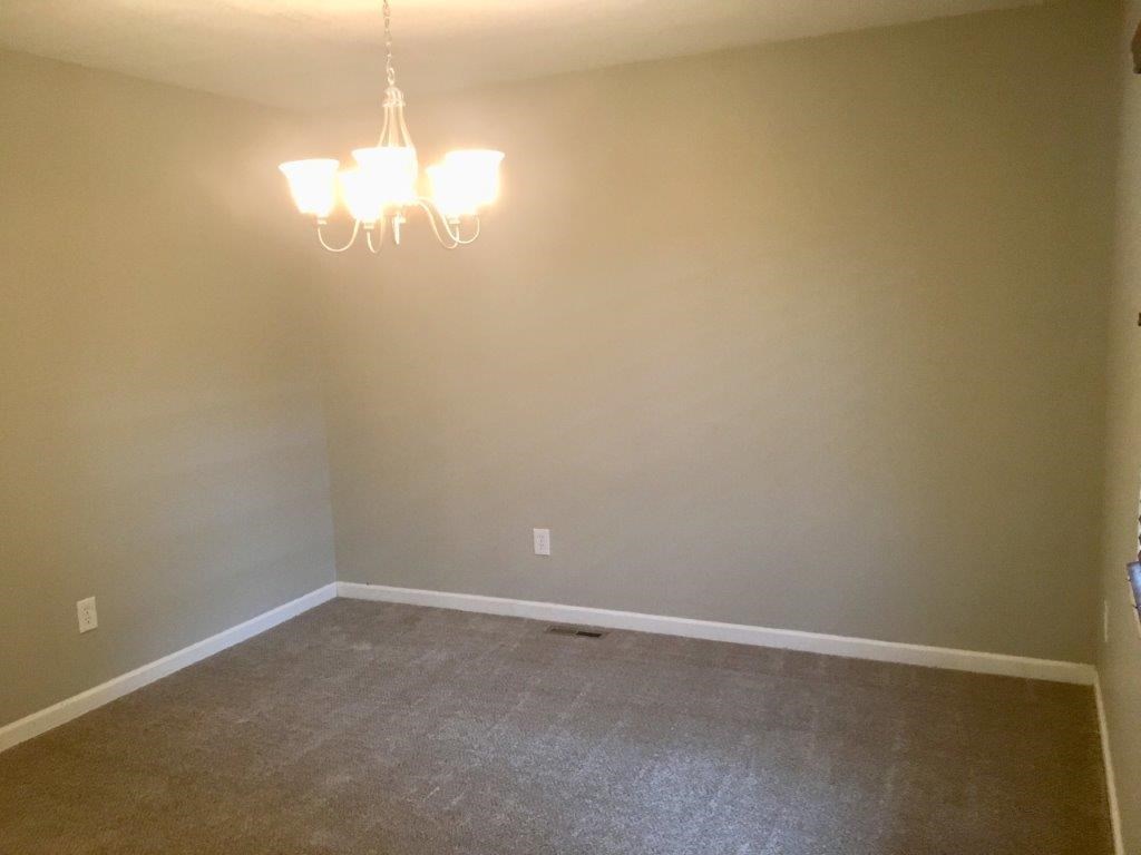 a empty room with a chandelier and a carpet