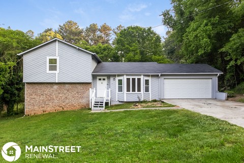 the front of a white house with a garage and a yard