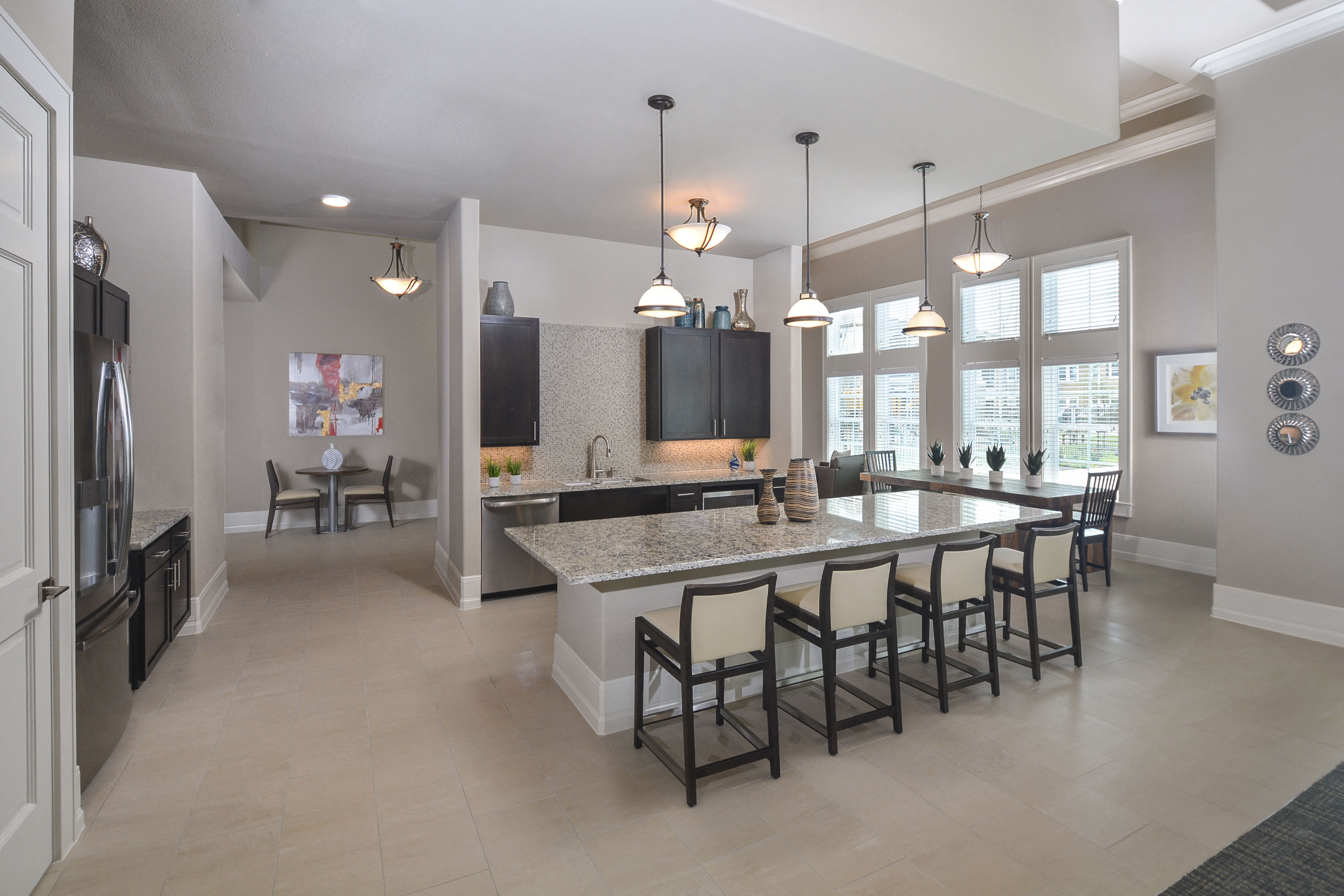 A kitchen with a large island and a refrigerator on the left.