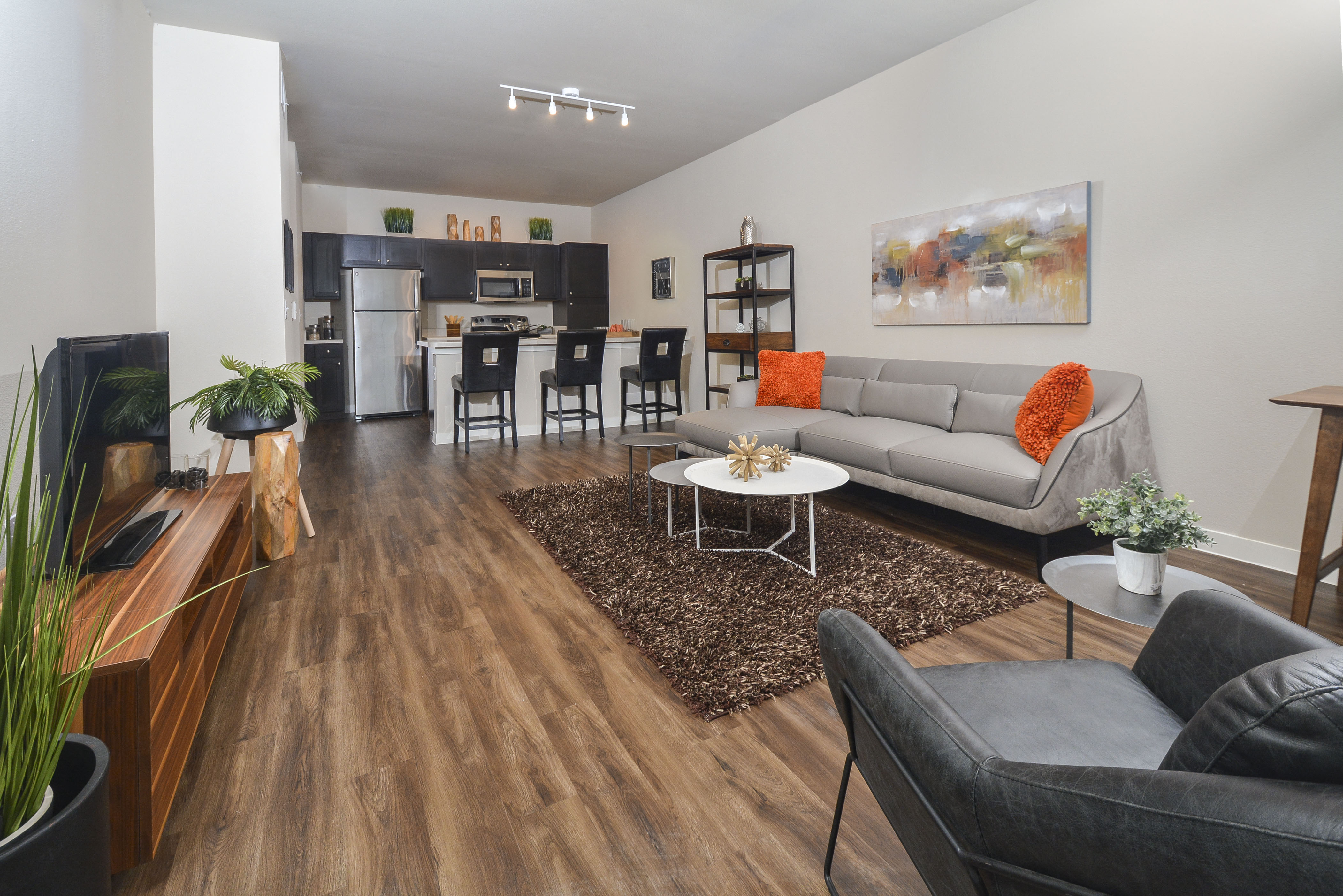 A modern living room with a grey sofa and a wooden floor.