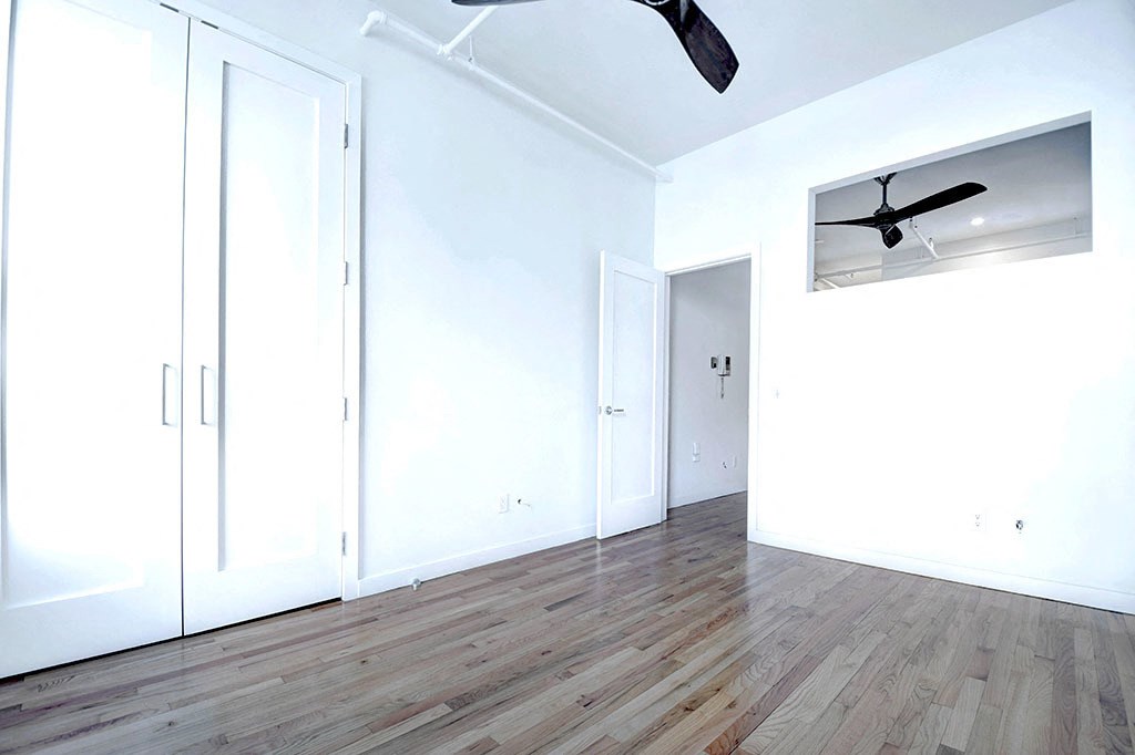 an empty room with white walls and a ceiling fan