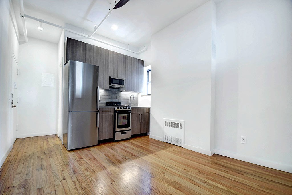 a renovated kitchen with stainless steel appliances and wooden floors