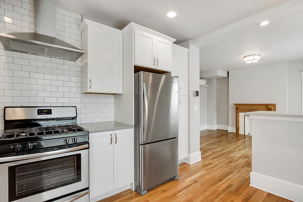 a kitchen with white cabinets and a stainless steel refrigerator