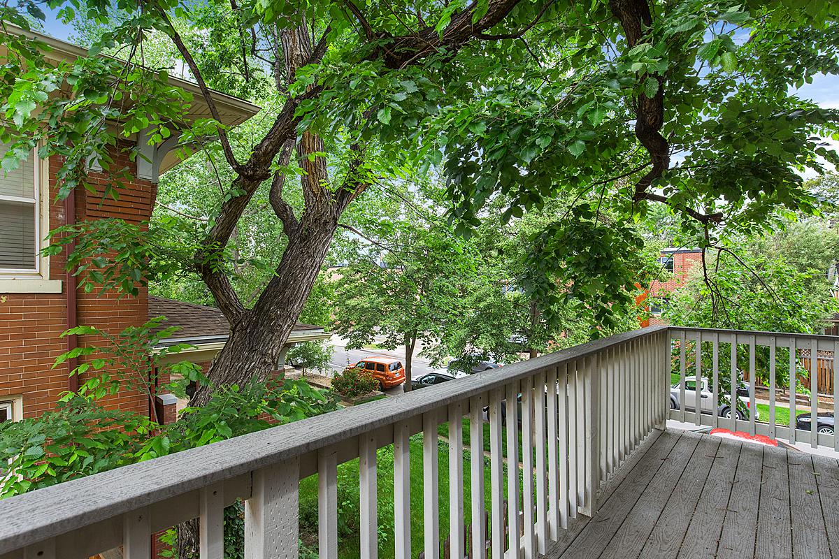 a balcony with a wooden railing and trees