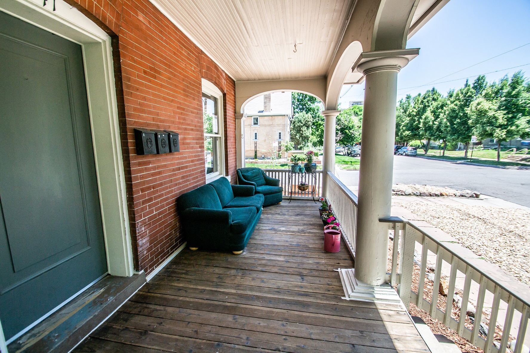 the front porch of a brick house with blue couches and a porch swing