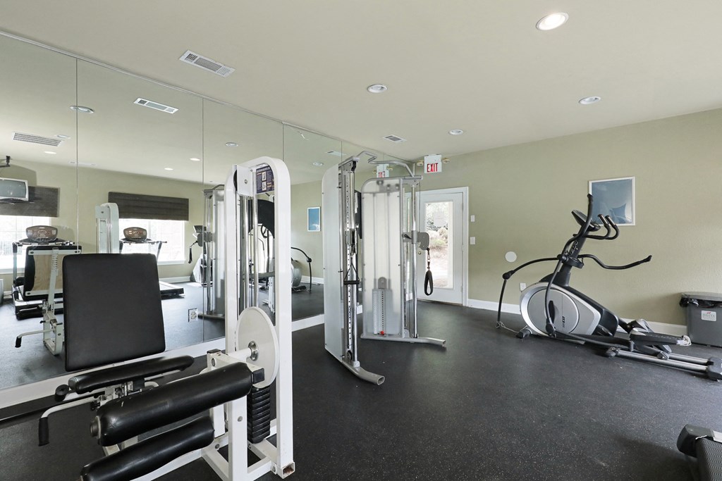 a gym with cardio equipment and mirrors on the wall