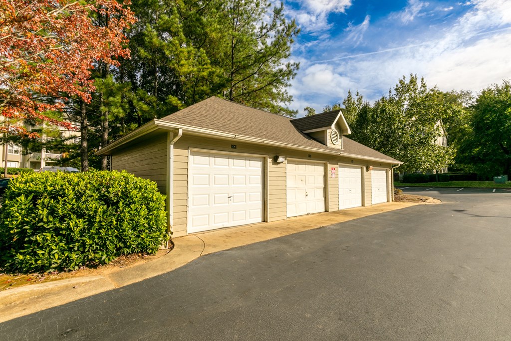 a garage with two white doors on the side of a driveway