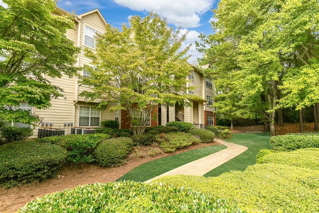 a pathway leading to a building with trees and bushes