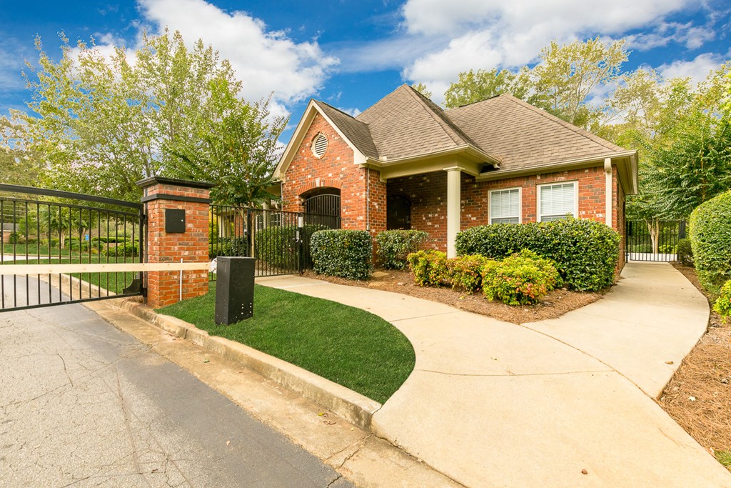 the front of a brick house with a sidewalk and a fence