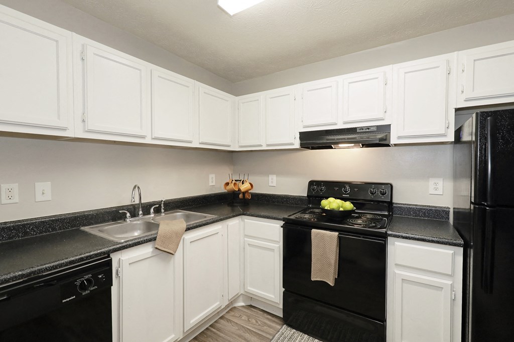 an empty kitchen with black appliances and white cabinets