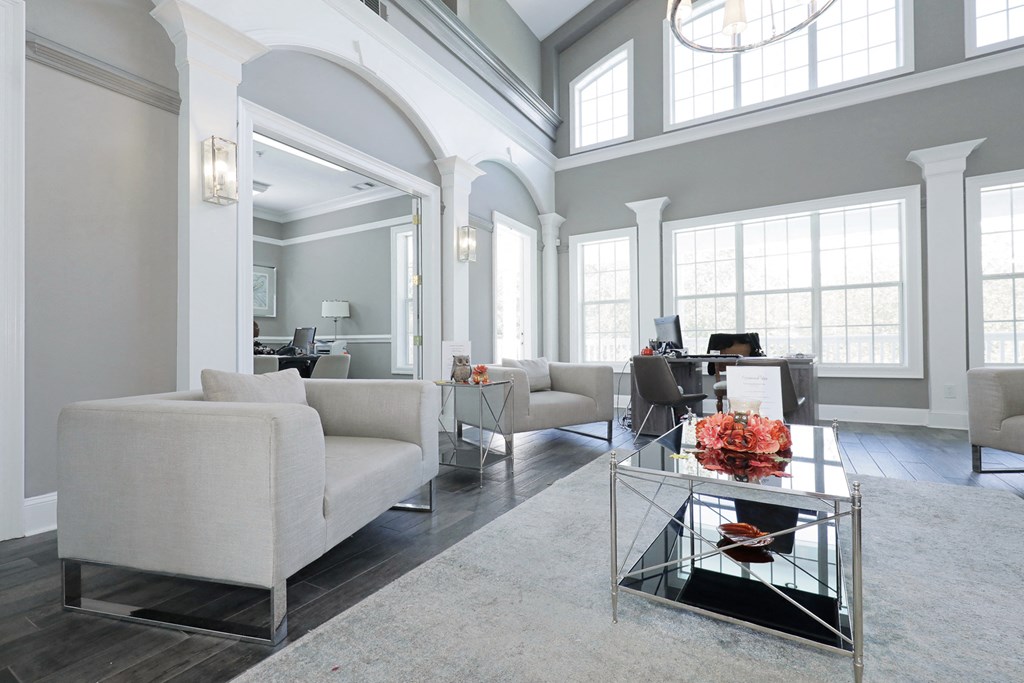 a living room with white furniture and large windows