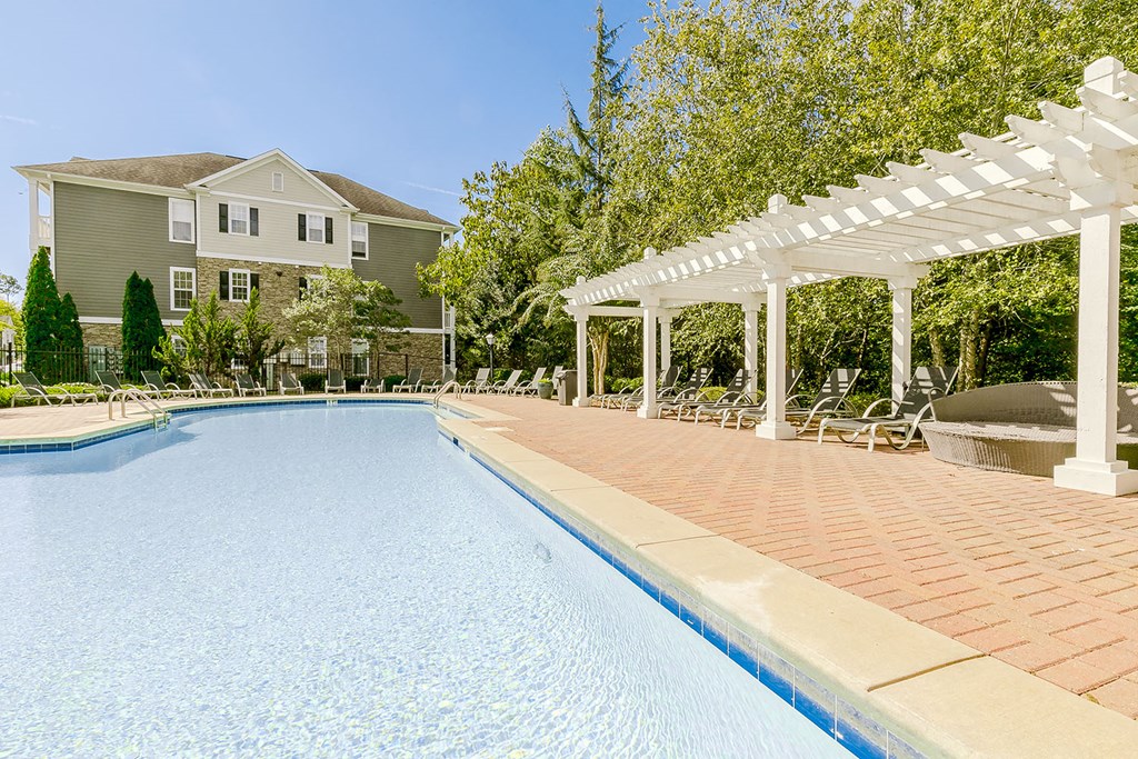 a swimming pool with a pavilion and a house in the background