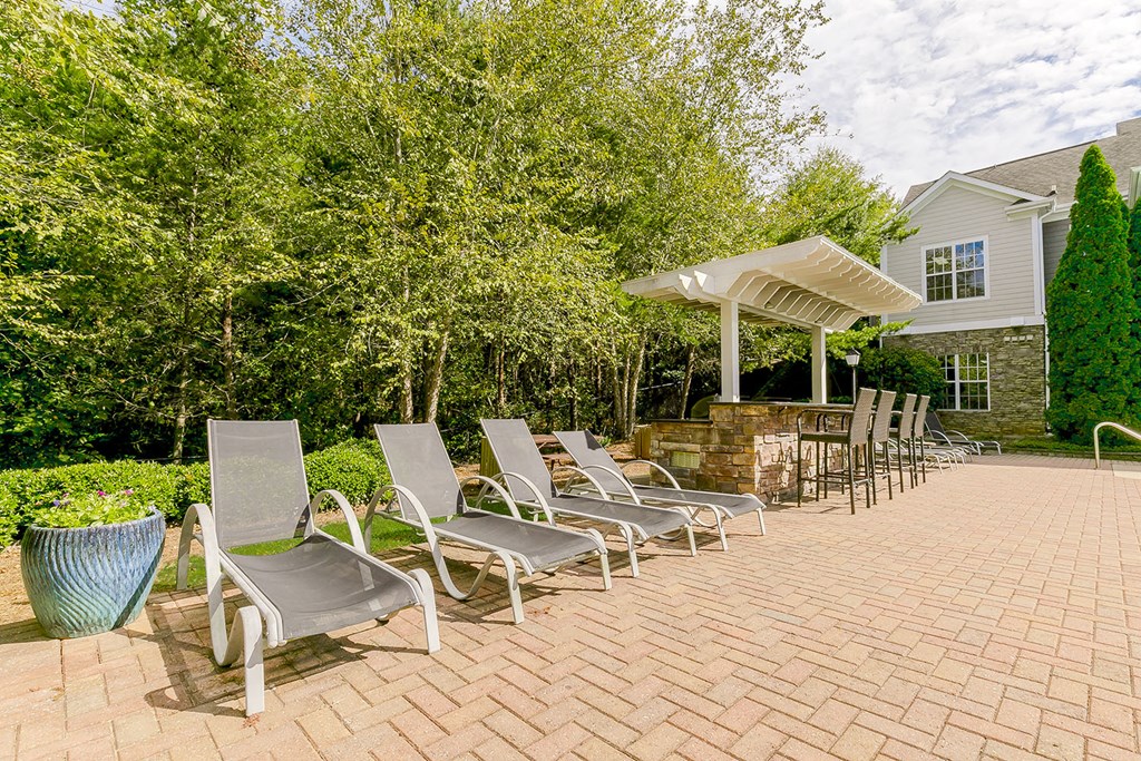 a patio with chairs and a gazebo and a house with trees