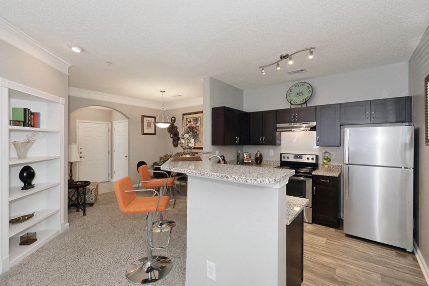the view of a kitchen and dining area with stainless steel appliances and a granite counter