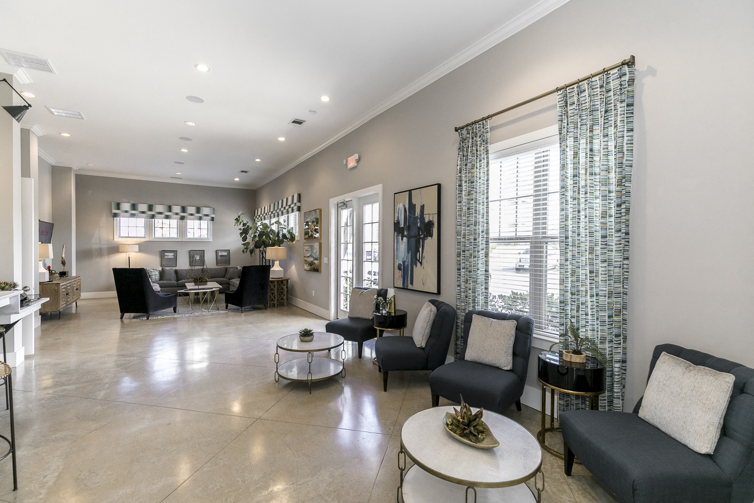 a living room with chairs and tables and windows