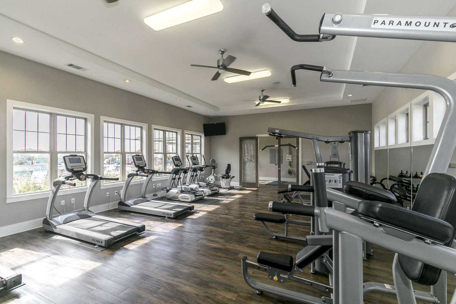 a gym with cardio equipment and windows in a building