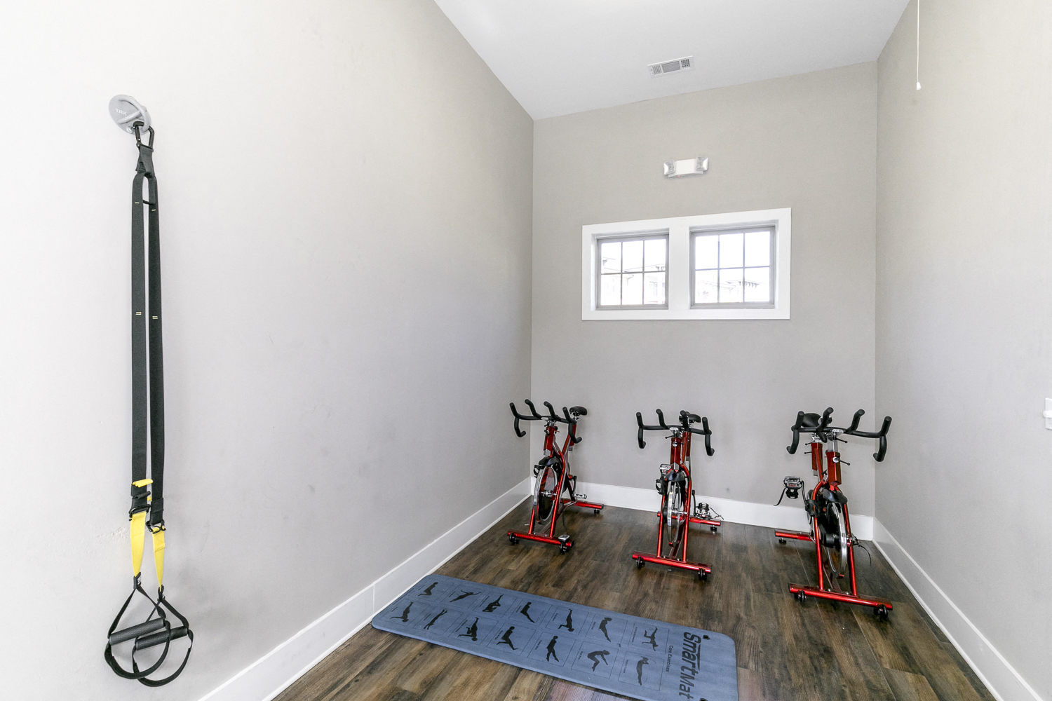 the gym with exercise equipment in a room with white walls and a window